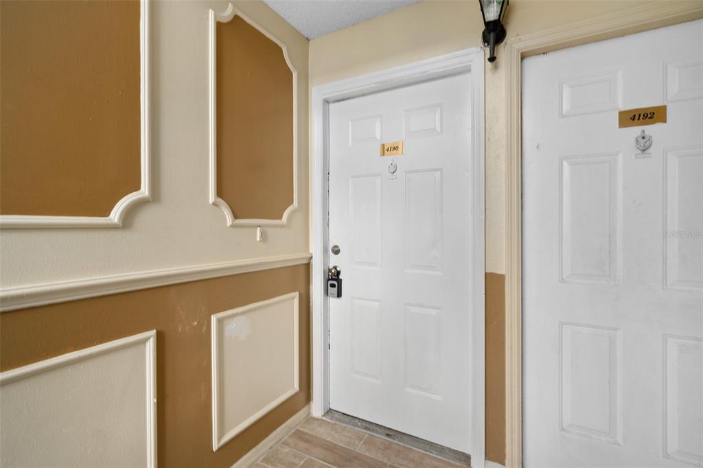 A hallway features two white doors numbered 4190 and 4192 with tan paneled walls — 4190 VERSAILLES DRIVE UNIT 4190D, ORLANDO, FL