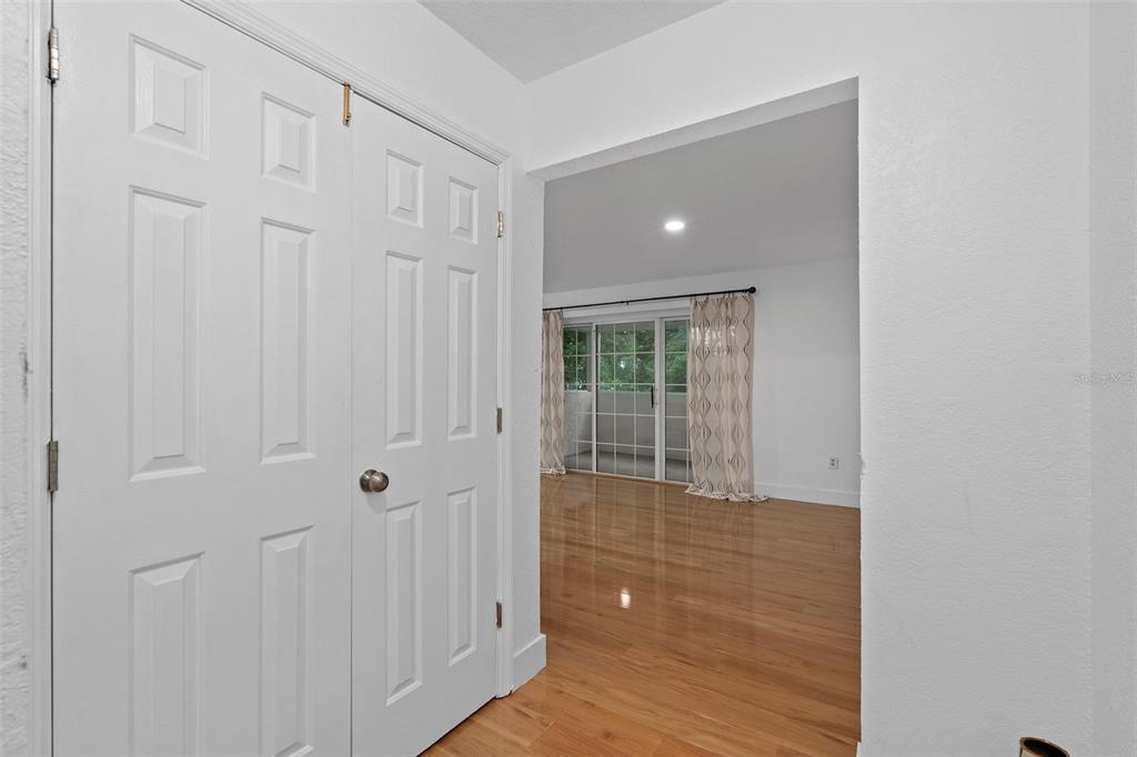 A white double-door closet opens into a room with hardwood floors and a sliding door — 4190 VERSAILLES DRIVE UNIT 4190D, ORLANDO, FL