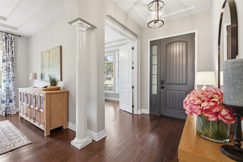 An entryway features dark wood floors, a gray front door, and a white decorative column — 17909 HOWSMOOR PLACE, LUTZ, FL