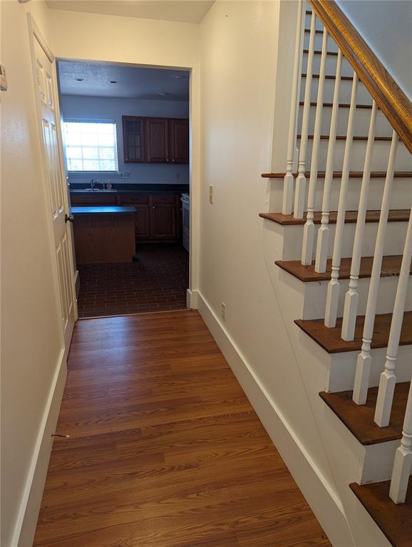 A hallway with wood-look flooring leads to a kitchen, with a staircase on the right — 20333 SUGARLOAF MOUNTAIN ROAD, CLERMONT, FL