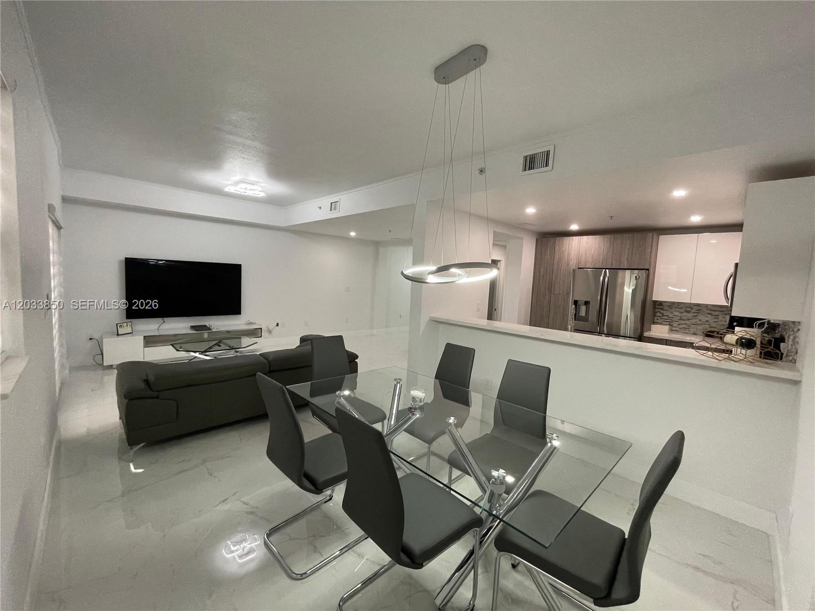 A modern open-concept living and dining area features white tile floors and a glass table — 10885 NW 89th Ter # 206, Doral FL 33178, DORAL, FL