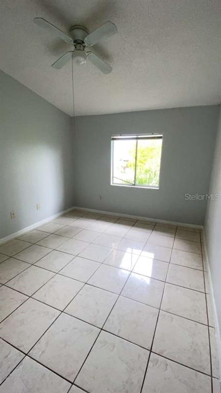 An empty room with light gray walls, a ceiling fan, and light-colored tiled flooring — 5214 VIA HACIENDA CIRCLE UNIT A306, ORLANDO, FL