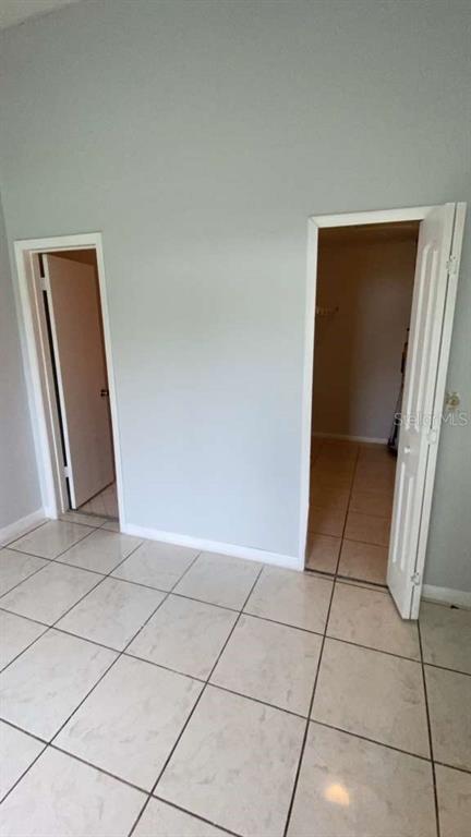 A room with light-colored tile flooring features two open doorways leading to adjacent spaces — 5214 VIA HACIENDA CIRCLE UNIT A306, ORLANDO, FL