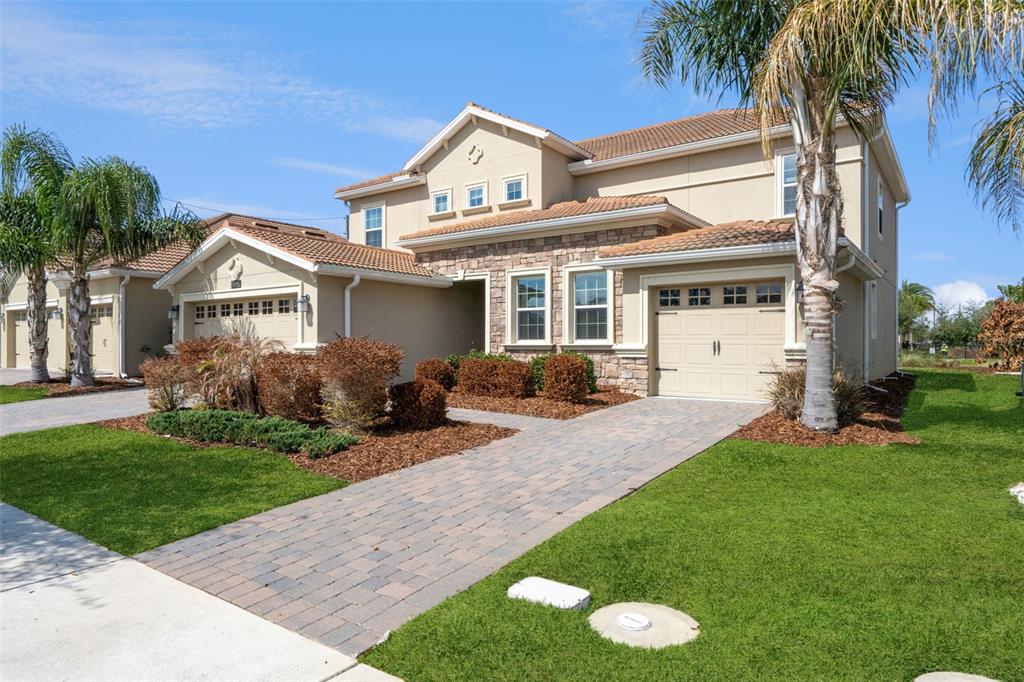 A two-story suburban house with a stone facade, beige stucco, and a paved driveway — 8995 CROQUET COURT, DAVENPORT, FL