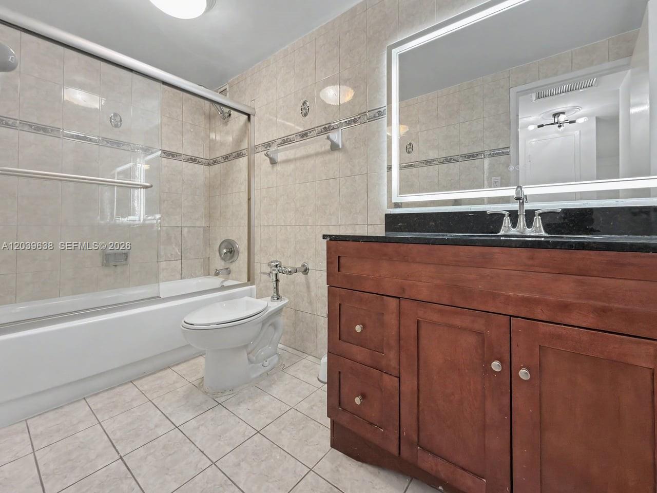 A bathroom features a wooden vanity, a black countertop, a toilet, and a tiled tub — 3301 NE 5th Ave # 307, Miami FL 33137, MIAMI, FL