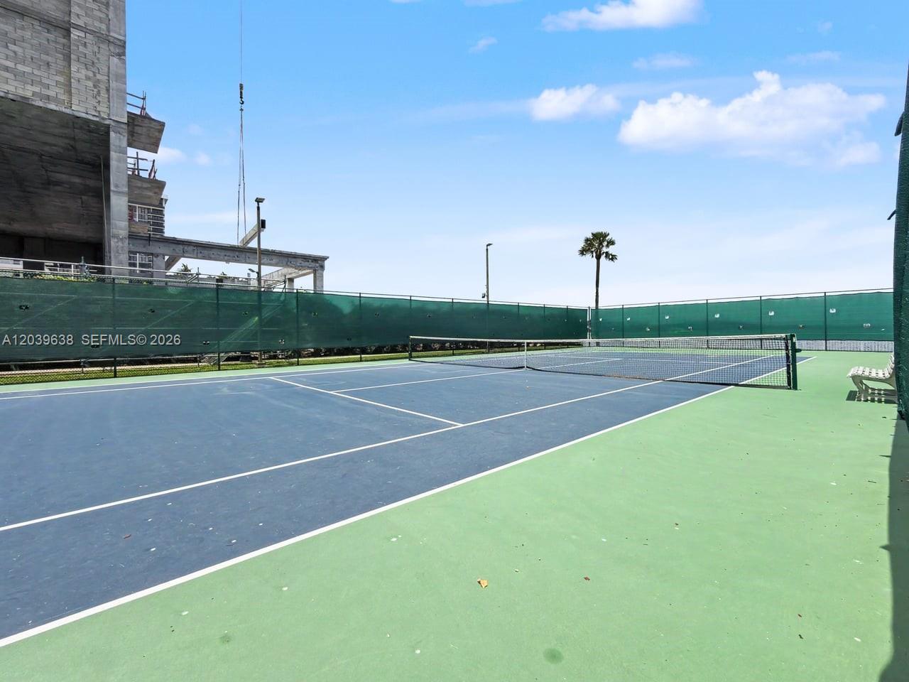 A tennis court with a blue playing surface and green surrounding area under a blue sky — 3301 NE 5th Ave # 307, Miami FL 33137, MIAMI, FL