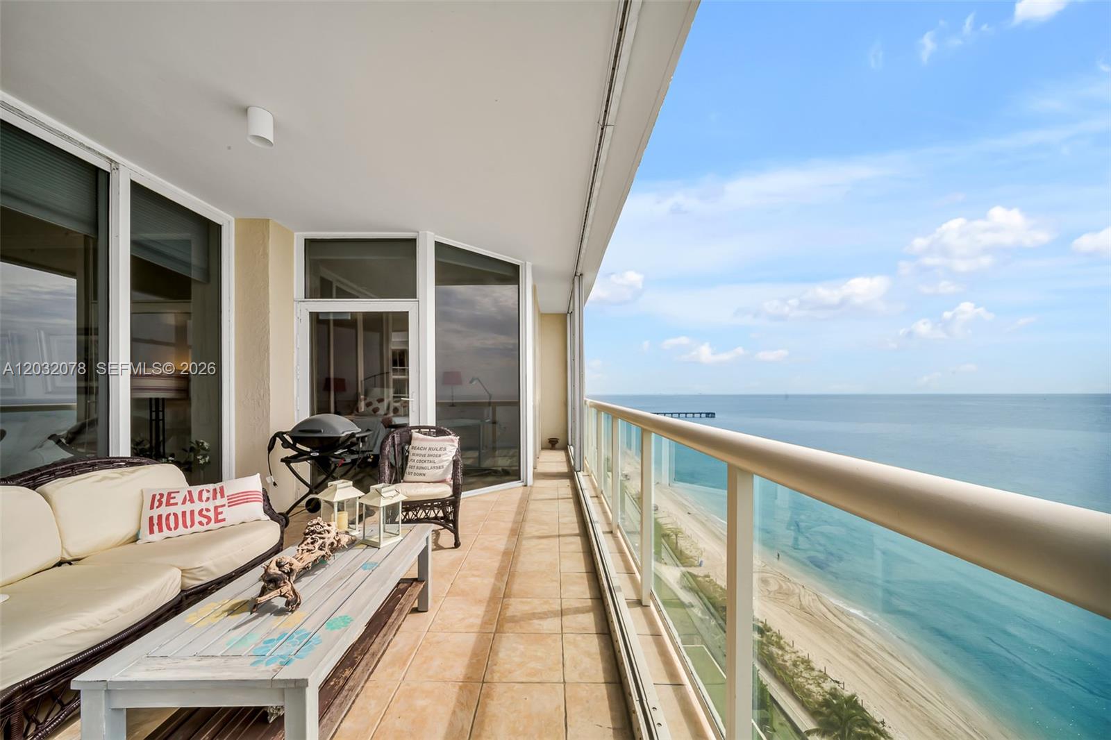 A balcony with outdoor furniture overlooks the ocean and a sandy beach — 6051 N Ocean Dr # 1501, Hollywood FL 33019, HOLLYWOOD, FL