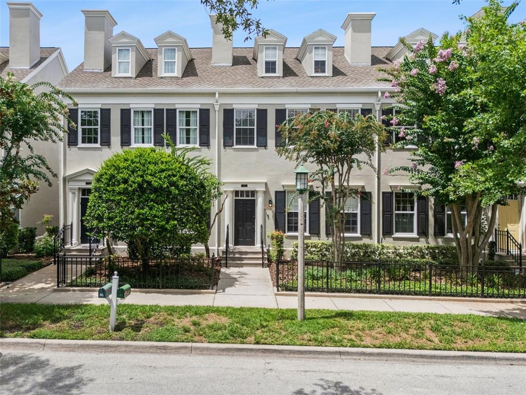 A row of three-story townhouses with light-colored stucco, black shutters, and dormer windows — 641 MULBERRY AVENUE, CELEBRATION, FL