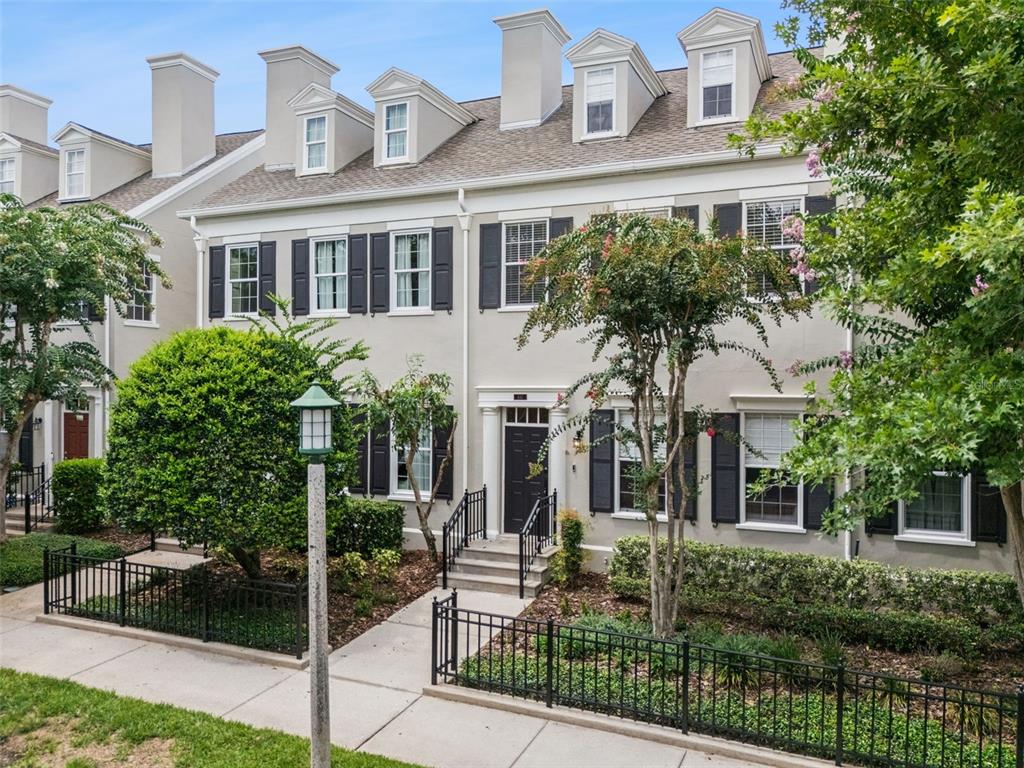 A three-story townhouse with a light gray facade, black shutters, and a front gated walkway — 641 MULBERRY AVENUE, CELEBRATION, FL