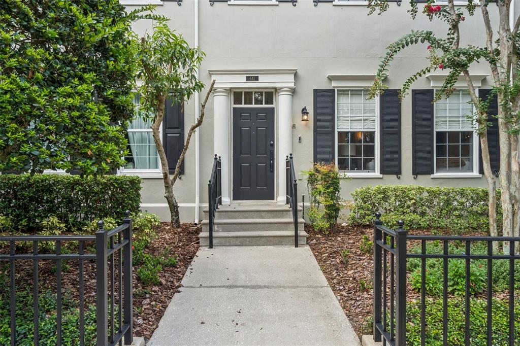 A concrete walkway leads to the front entrance of a house with black shutters — 641 MULBERRY AVENUE, CELEBRATION, FL