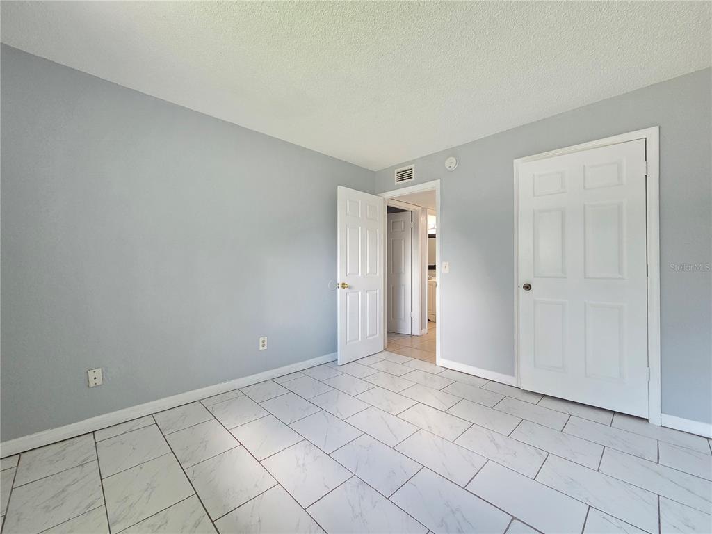 An empty room features light gray walls, white trim, and white marble-look tile flooring — 605 NORTHLAKE BOULEVARD UNIT 63, ALTAMONTE SPRINGS, FL
