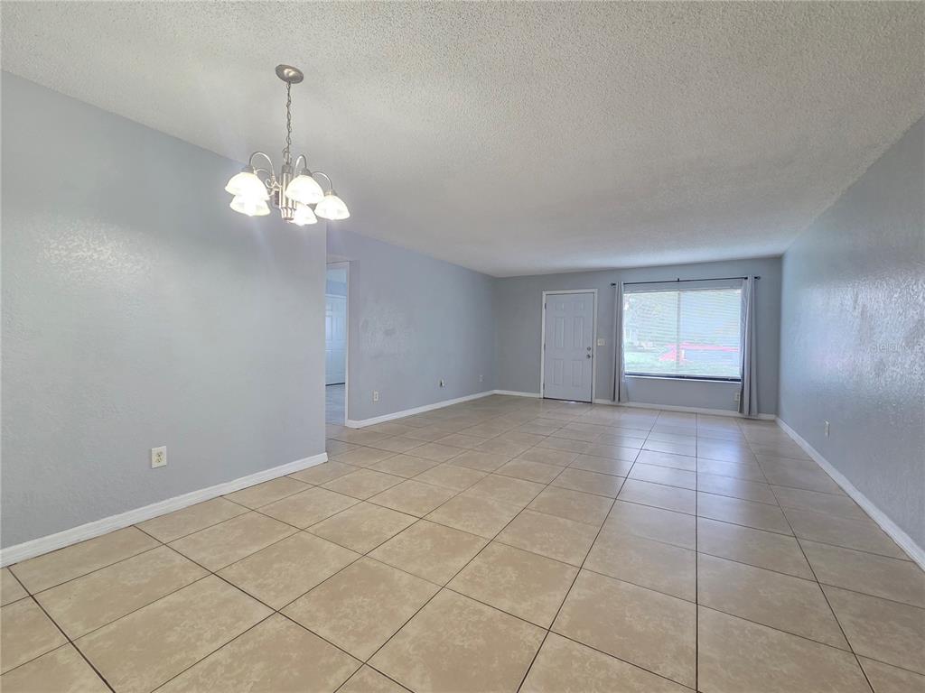 An empty room with light blue walls, tile flooring, a chandelier, and a front door — 605 NORTHLAKE BOULEVARD UNIT 63, ALTAMONTE SPRINGS, FL