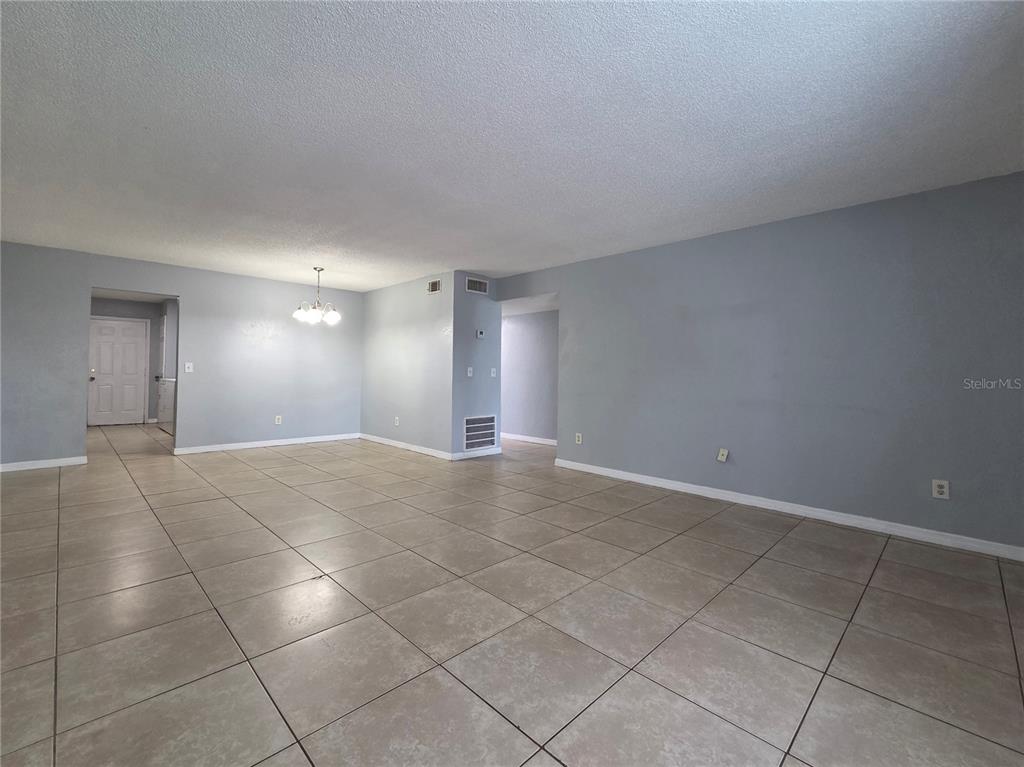 An empty room features light gray walls, beige tile flooring, and a central light fixture — 605 NORTHLAKE BOULEVARD UNIT 63, ALTAMONTE SPRINGS, FL