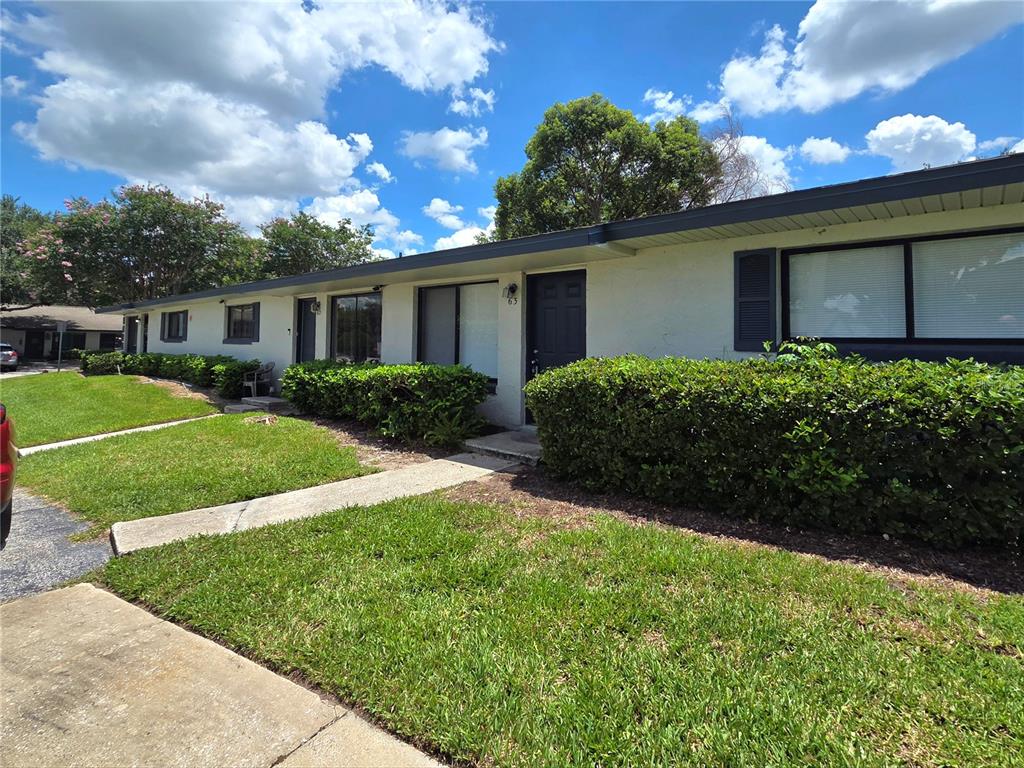 A single-story apartment building with white stucco walls, dark shutters, and a manicured hedge — 605 NORTHLAKE BOULEVARD UNIT 63, ALTAMONTE SPRINGS, FL
