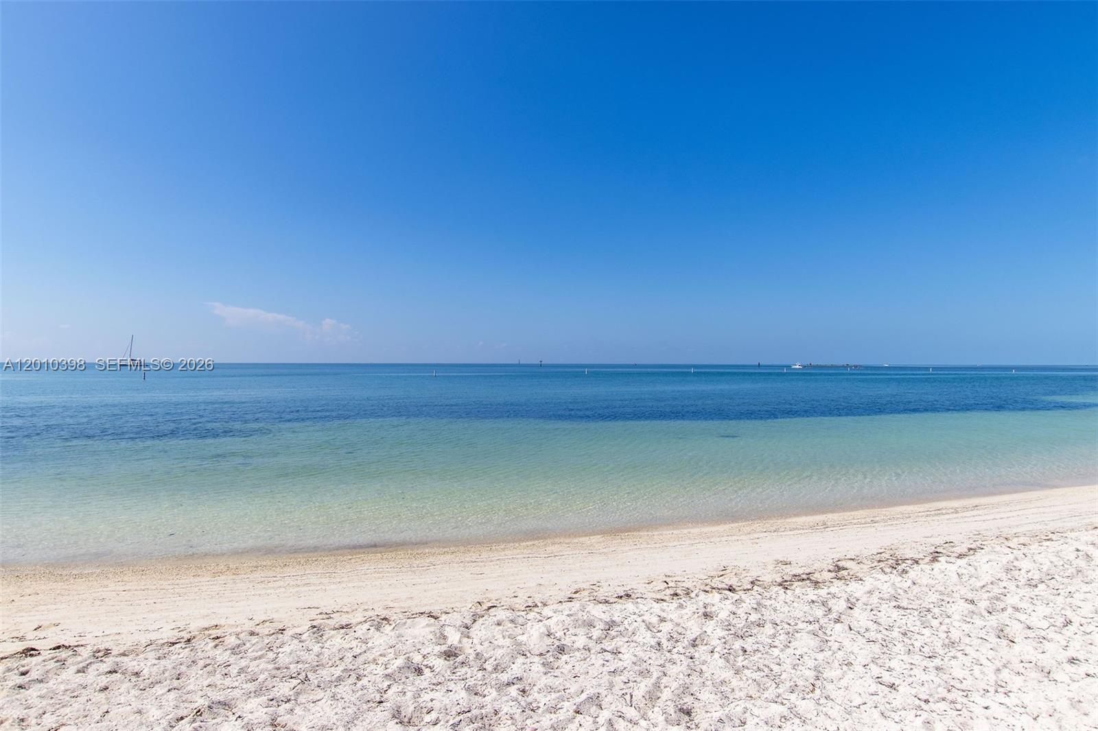 A sandy beach meets clear blue water under a bright, cloudless sky — 320 Calzada De Bougainville, Marathon FL 33050, MARATHON, FL