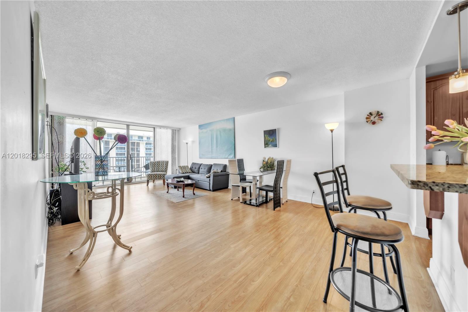 An open-concept living and dining area features light wood flooring, white walls, and balcony access — 2101 S Ocean Dr, Hollywood FL 33019, HOLLYWOOD, FL