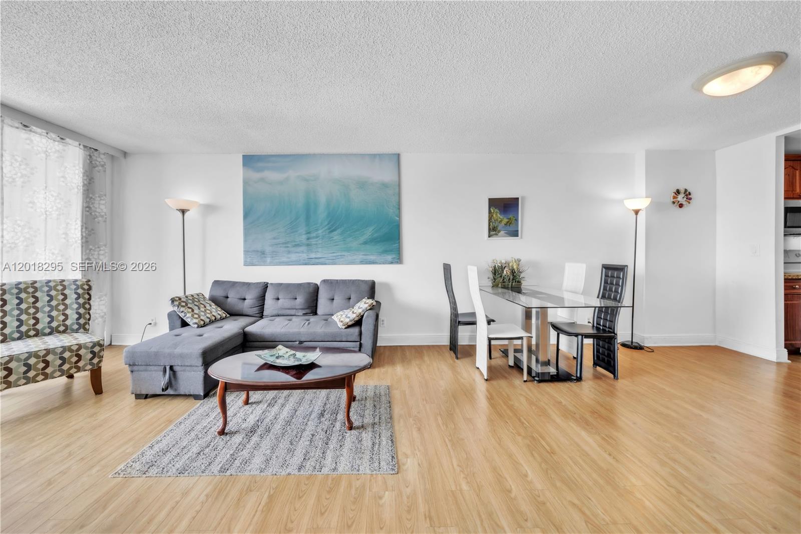 A living and dining room features light wood flooring, a gray sectional, and glass table — 2101 S Ocean Dr, Hollywood FL 33019, HOLLYWOOD, FL