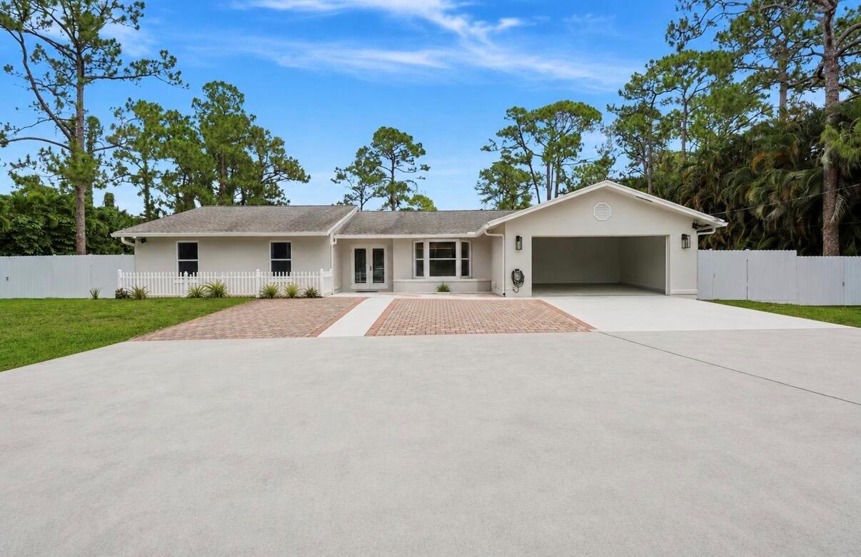 A single-story house with a beige exterior, a two-car garage, and a brick-paved driveway — 11849 N 59th St Street N, FL 33411, FL