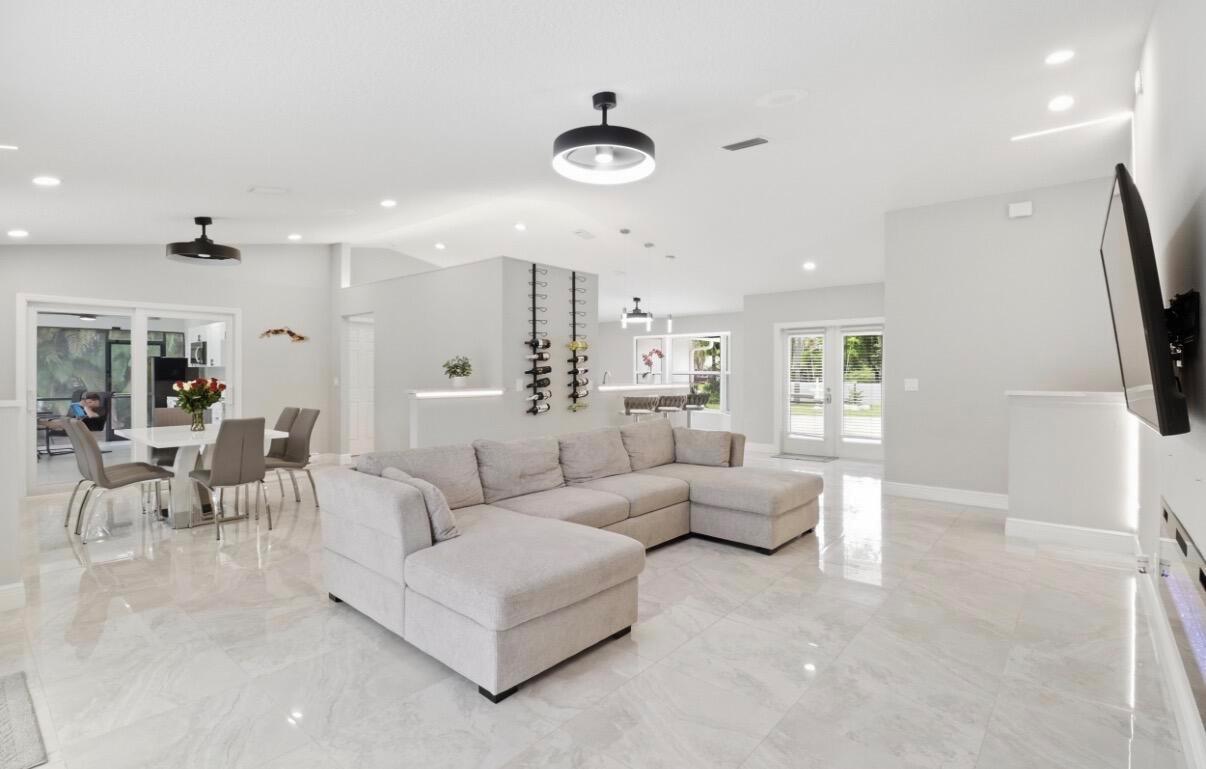 A spacious open-concept living room features a large sectional sofa, tile flooring, and dining area — 11849 N 59th St Street N, FL 33411, FL