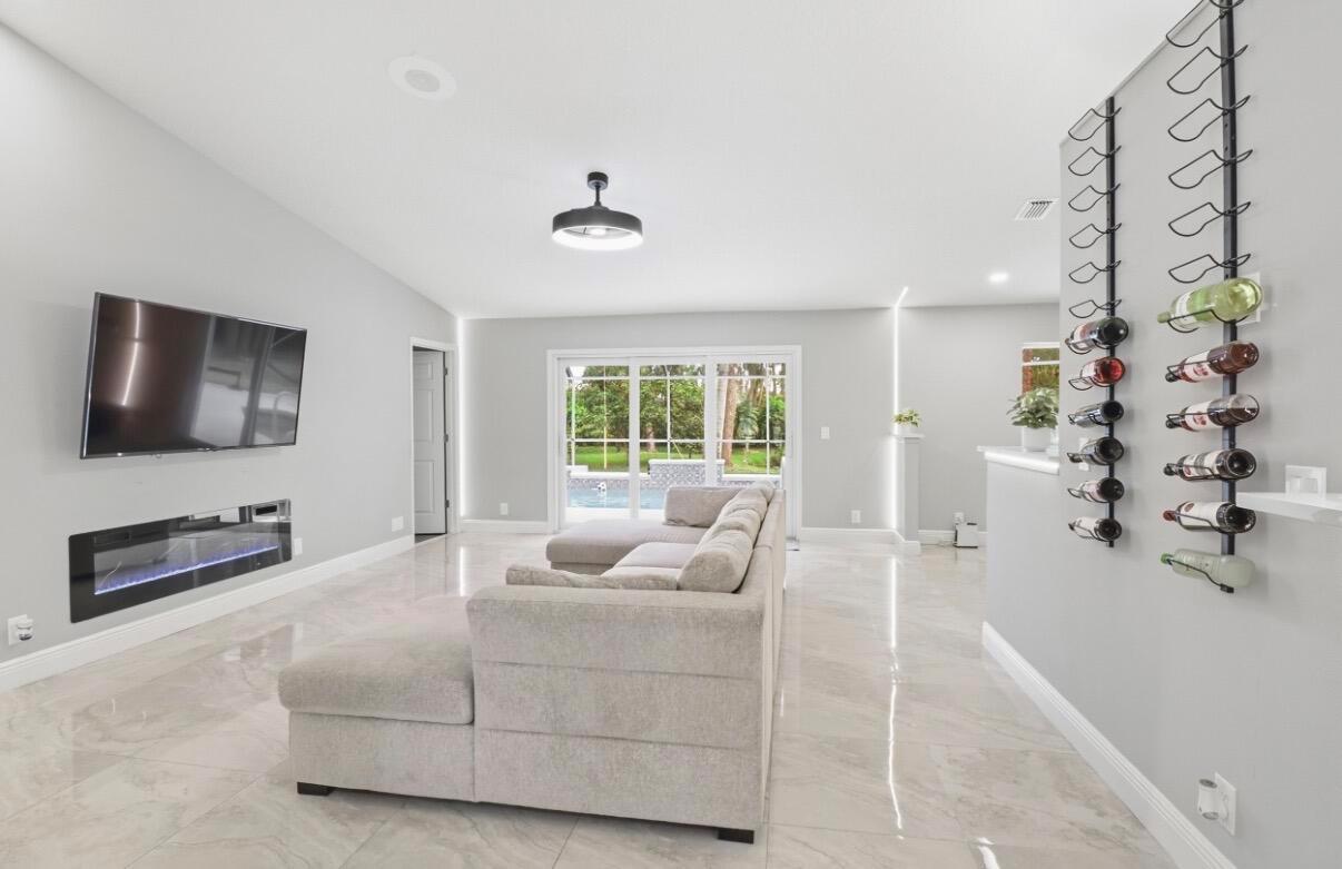A living room with a sectional sofa, wall-mounted television, electric fireplace, and wine rack — 11849 N 59th St Street N, FL 33411, FL