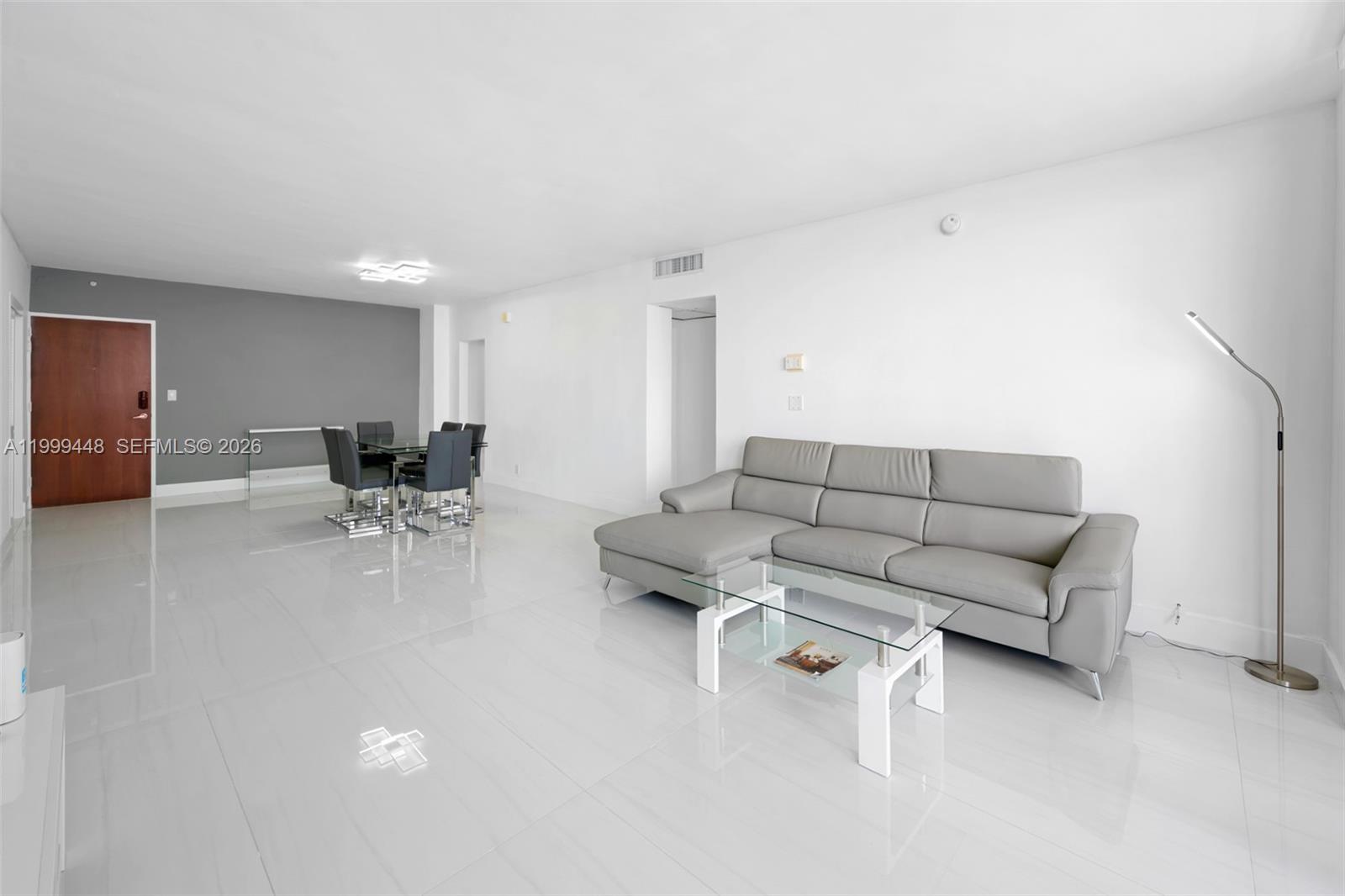 A living and dining area features white tile floors, a gray sectional sofa, and white walls — 4001 S Ocean Dr # 15B, Hollywood FL 33019, HOLLYWOOD, FL