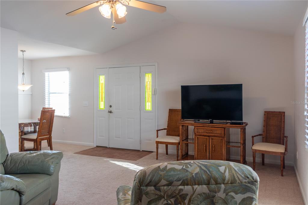 A living room features a television on a wicker stand, two chairs, and a front door — 4209 JACARANDA DRIVE, LAKE WALES, FL