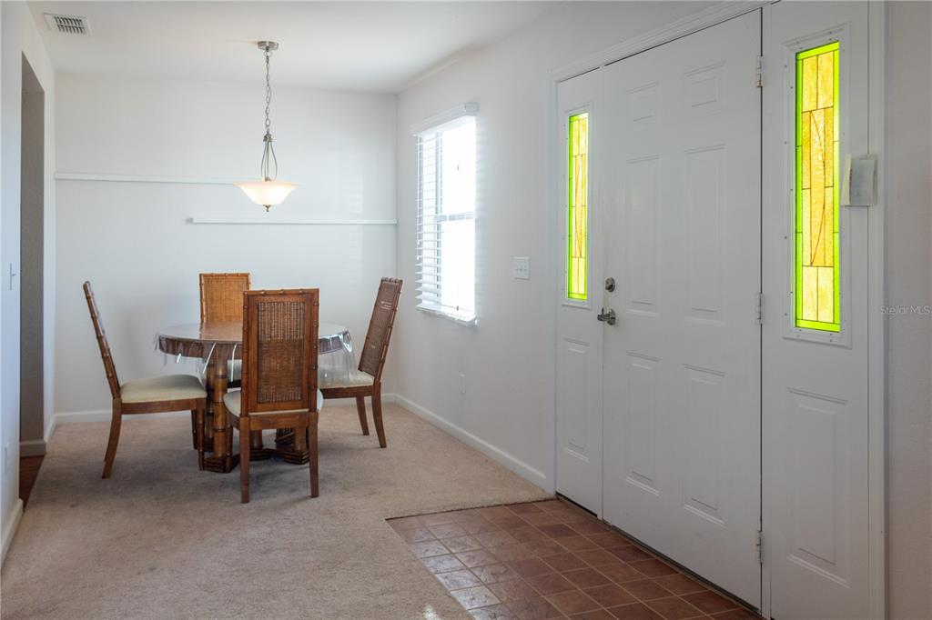 A dining area with a round table, four chairs, and a white front door — 4209 JACARANDA DRIVE, LAKE WALES, FL
