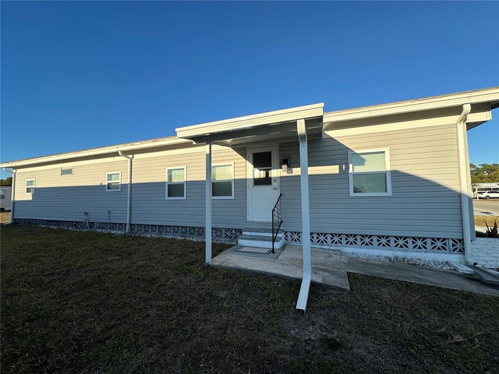The exterior of a light gray manufactured home features a small covered front porch — 5409 HOLIDAY PARK BOULEVARD, NORTH PORT, FL
