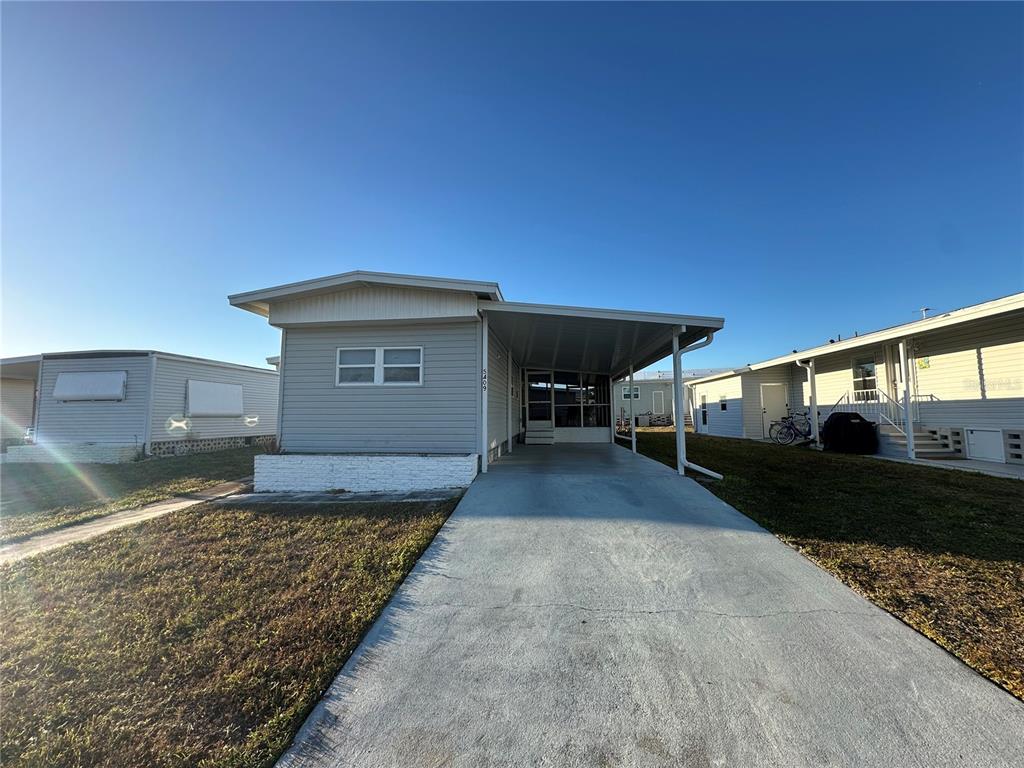 A single-story manufactured home features light gray siding, a concrete driveway, and a covered carport — 5409 HOLIDAY PARK BOULEVARD, NORTH PORT, FL
