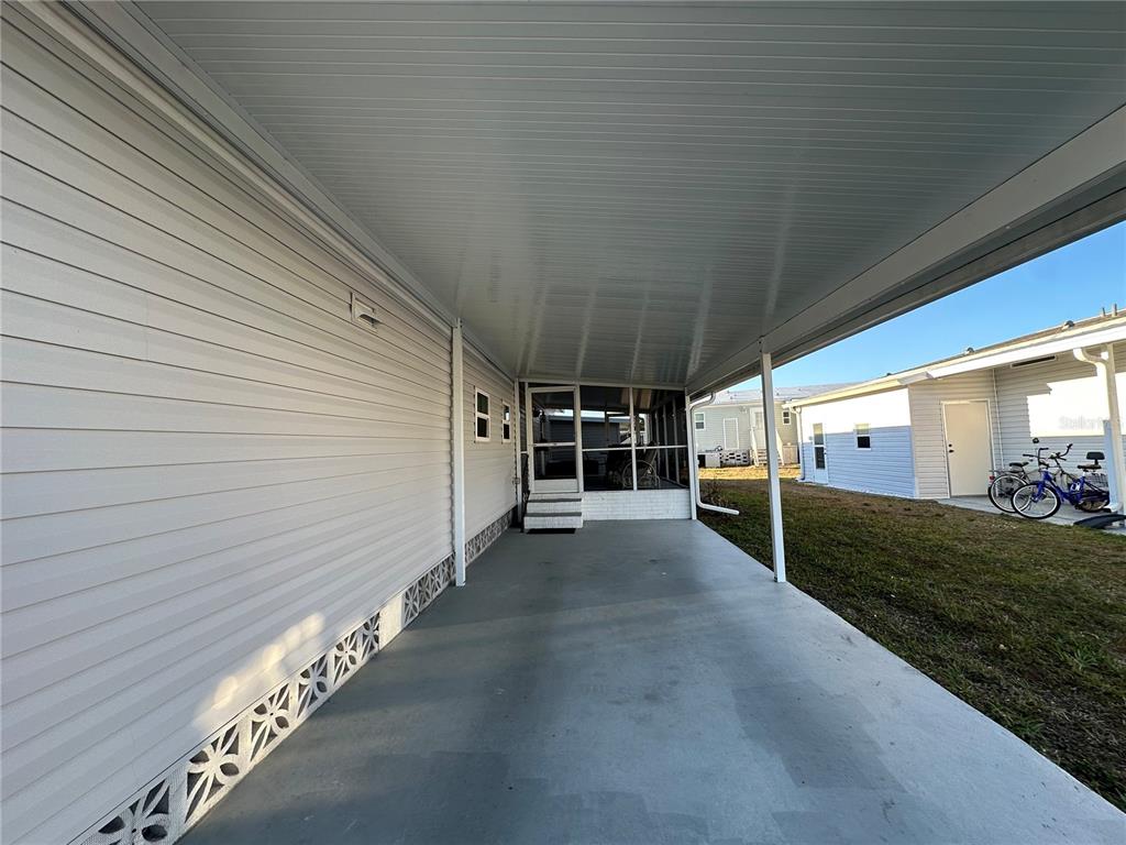 A covered concrete carport sits beside a mobile home with white siding and lattice skirting — 5409 HOLIDAY PARK BOULEVARD, NORTH PORT, FL