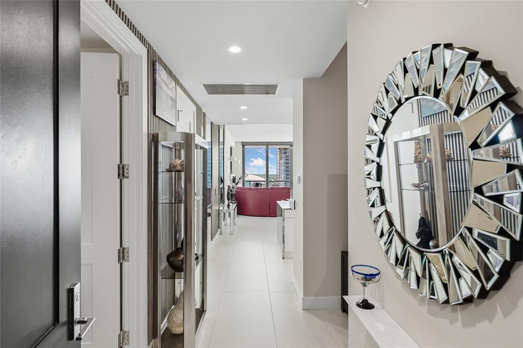 A hallway with white tile floors leads to a living area featuring a red sofa — 301 1ST STREET S UNIT 2705, ST PETERSBURG, FL