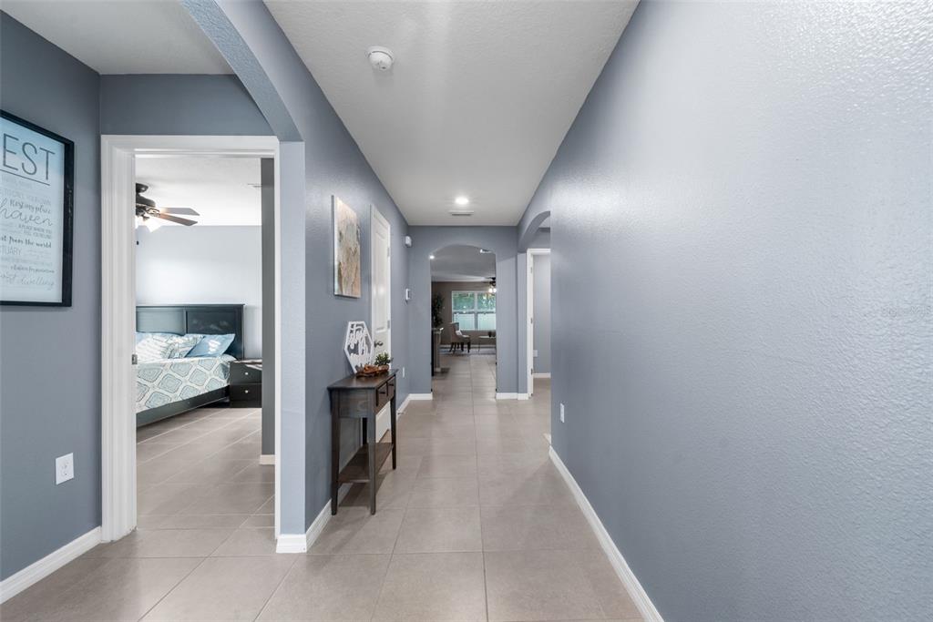 A hallway with gray walls and tile flooring leads to an arched entryway — 25119 NW 8TH ROAD, NEWBERRY, FL