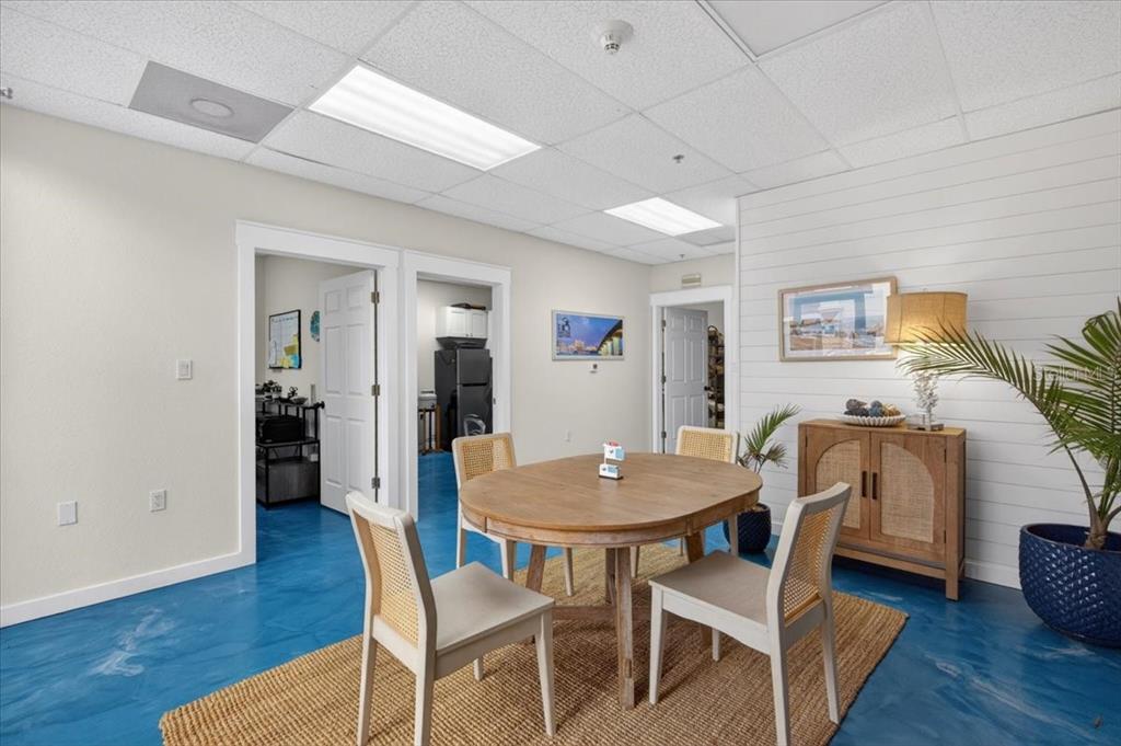 A dining area features a round wooden table, four chairs, and blue epoxy flooring — 6321 PORTER UNIT 3, SARASOTA, FL