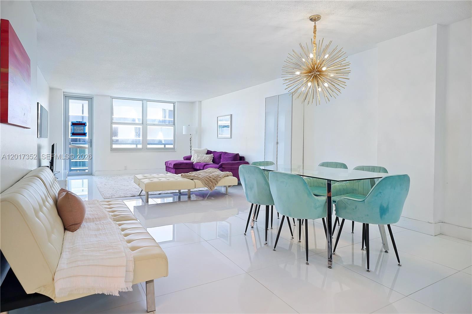 A bright living and dining area features white tile floors, a purple sofa, and turquoise chairs — 9511 Collins Ave # 901, Surfside FL 33154, SURFSIDE, FL