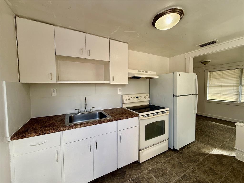 A kitchen with white cabinets, a stainless steel sink, a white stove, and a refrigerator — 3908 S NASHVILLE AVENUE, ORLANDO, FL
