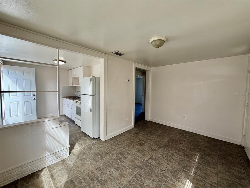 A tiled dining area leads into a kitchen with white cabinets and a refrigerator — 3908 S NASHVILLE AVENUE, ORLANDO, FL