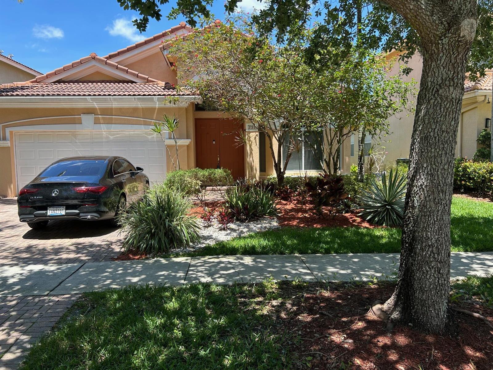 A tan house with a tile roof, a black car in the driveway, and landscaping — 759 Gazetta Way, West Palm Beach FL 33413, WEST PALM BEACH, FL