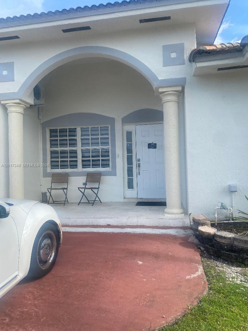 The exterior of a house features a covered porch with two chairs and white columns — 14640 SW 180th St, Miami FL 33177, MIAMI, FL