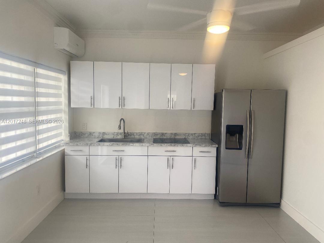 A kitchen features white cabinets, a stainless steel refrigerator, and a marble-patterned countertop — 14640 SW 180th St, Miami FL 33177, MIAMI, FL