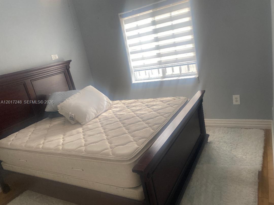 A bedroom features a dark wood bed frame, a white mattress, and a window with blinds — 14640 SW 180th St, Miami FL 33177, MIAMI, FL
