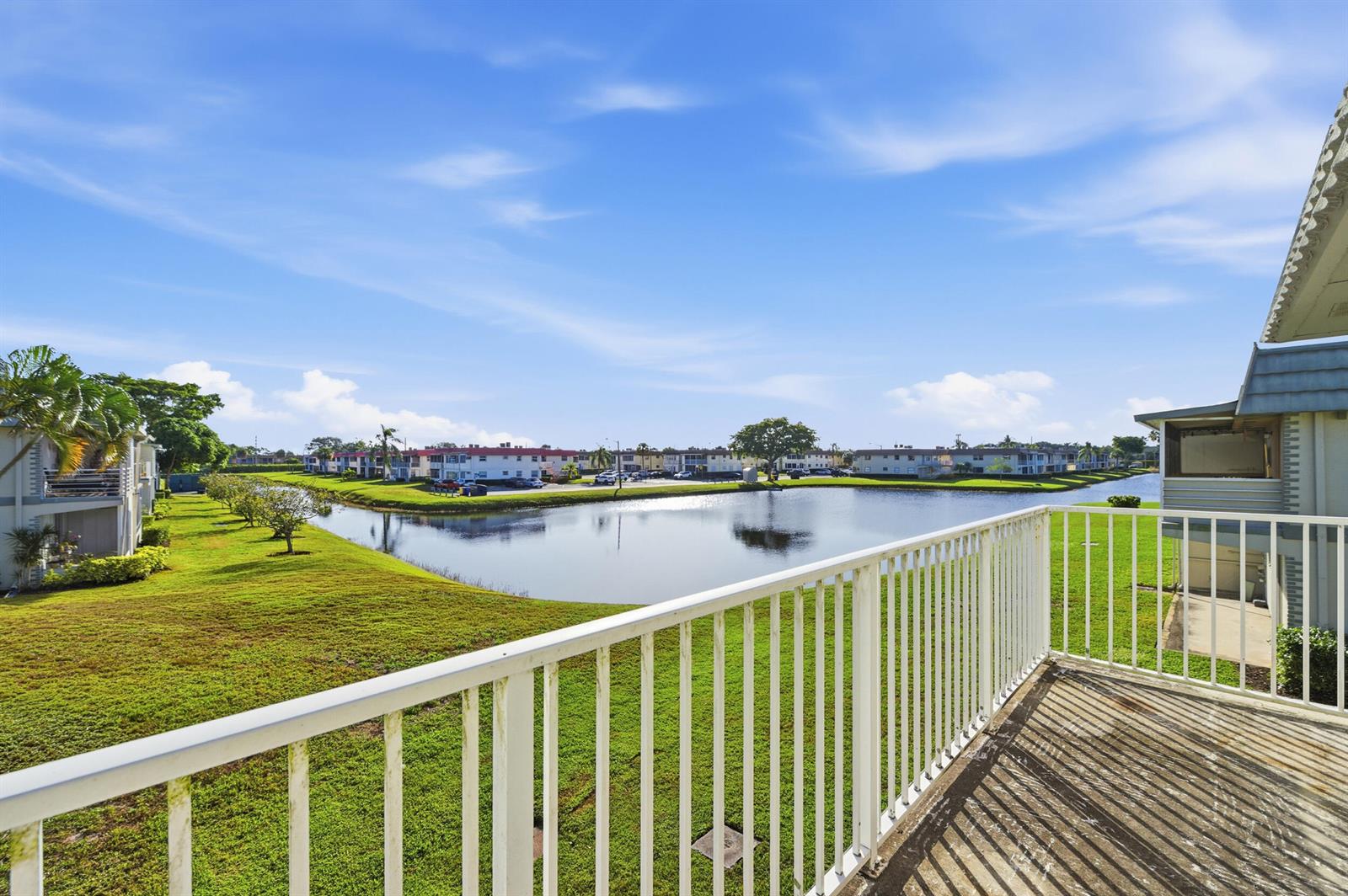 A balcony with a white railing overlooks a grassy lawn and a small lake — 710 Monaco O, Delray Beach FL 33446, DELRAY BEACH, FL