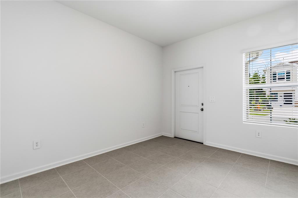 A room with white walls, gray tile flooring, a white door, and a window — 3092 CHROMATIC STREET, KISSIMMEE, FL
