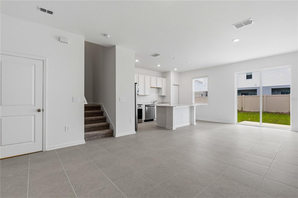 An open-concept kitchen with white cabinets and an island overlooks a tiled living area — 3092 CHROMATIC STREET, KISSIMMEE, FL