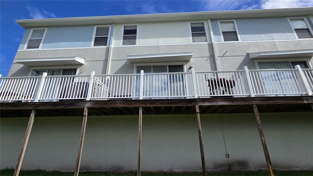 A multi-story townhouse exterior features a raised wooden deck with white railings and sliding doors — 1507 TALISKER DRIVE, CLEARWATER, FL