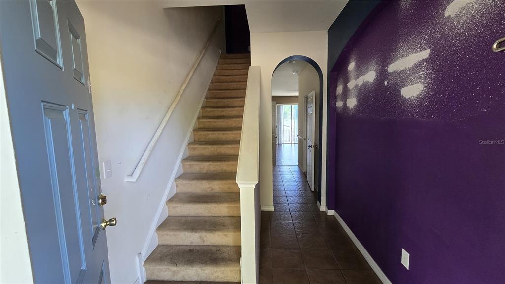 An entryway features a carpeted staircase, a tiled hallway, and a purple accent wall — 1507 TALISKER DRIVE, CLEARWATER, FL