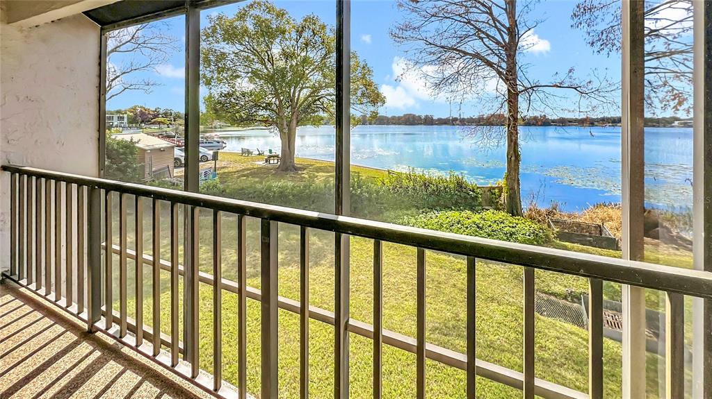 A screened-in balcony overlooks a grassy lawn and a lake with trees — 630 KILLARNEY BAY COURT UNIT 3, WINTER PARK, FL