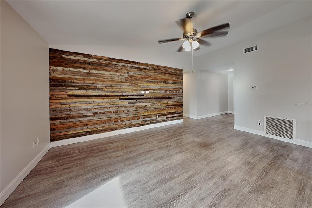 A room with wood-plank accent wall, gray flooring, and a ceiling fan — 2709 MANOR HILL DRIVE, BRANDON, FL