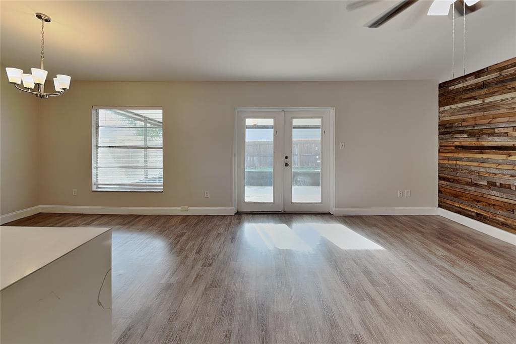 A living room features wood-look flooring, a rustic wood accent wall, and double glass doors — 2709 MANOR HILL DRIVE, BRANDON, FL