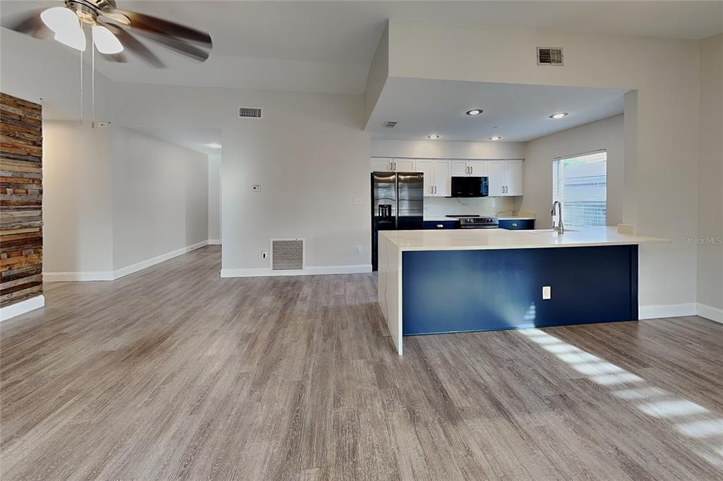 An open-concept kitchen features a blue island, white cabinets, and wood-look flooring — 2709 MANOR HILL DRIVE, BRANDON, FL