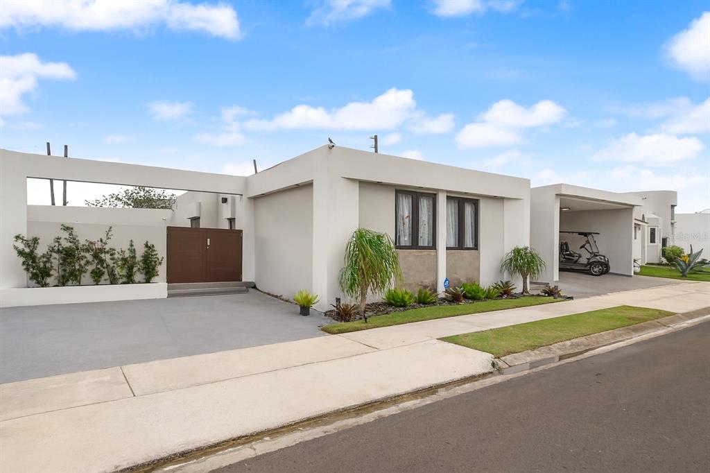 A modern single-story house with a flat roof, white exterior, and a covered carport — JJ-12 CALLE ROSA DE LOS VIENTOS, DORADO, PR